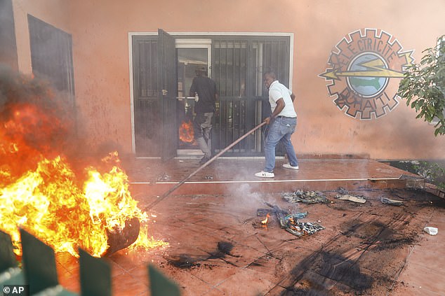 Workers put out a fire at the Haitian electricity company's office after it was targeted by protesters