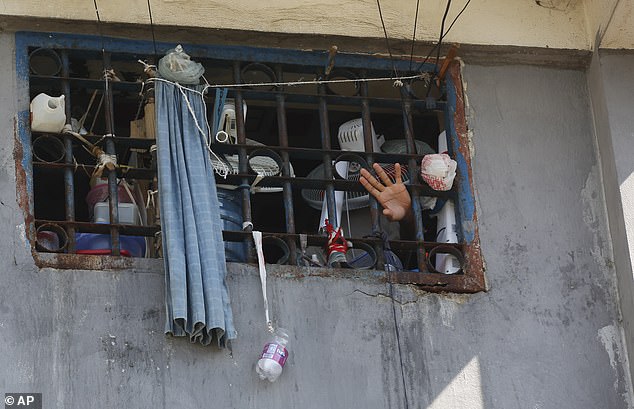 Prisoners wave their hands from the windows of the prison where armed gangs stormed at night