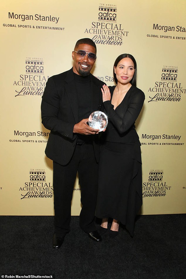 Foxx posed next to actress Jurnee Smollett as he held up a glass plaque with which he had been awarded