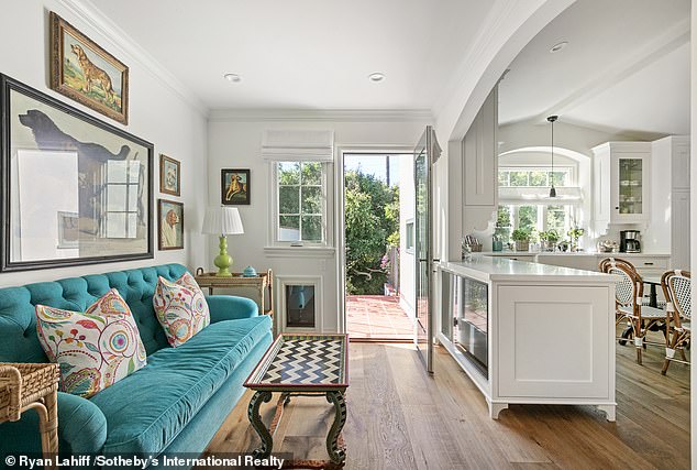 The updated kitchen features an island that surrounds a small sitting area and beyond that a door leading to a paved patio that overlooks the grassy backyard.