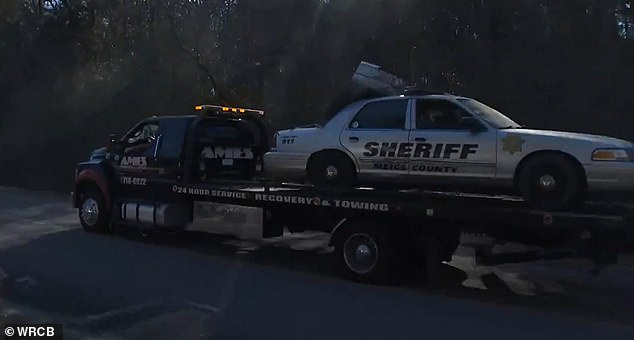 The deputy's car is seen being towed after being pulled from the Tennessee River