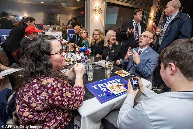 Supporters of former US president and presidential hopeful Donald Trump cheer as he is declared the winner during a rally in Virginia 