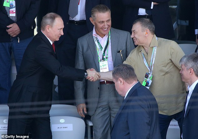 Russian President Vladimir Putin (L) shakes hands with billionaire businessman Arkady Rotenberg (R) as his brother Boris Rotenberg (C) looks on