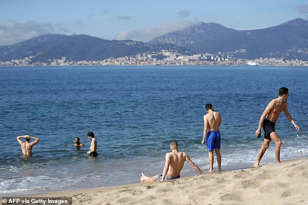 Men bathe in the 14°C sea during a warm weekend, with the Sanguinaires Islands in the background, on the French Mediterranean island of Corsica, in Porticcio, February 18, 2024