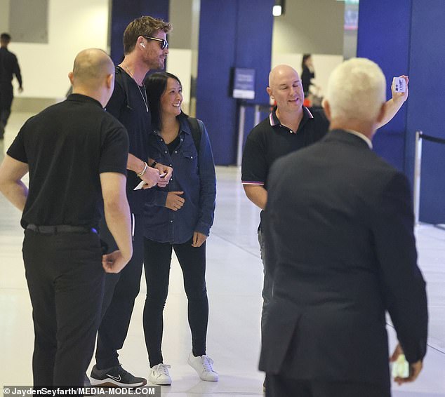 The star appeared distracted as he strolled through the terminal with a pair of AirPods in his ears, but paused for a moment, greeted by a group of fans asking for selfies