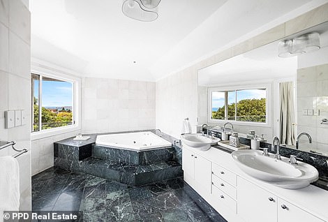 The bathroom features a double sink, deep blue-green marble and a raised spa bath