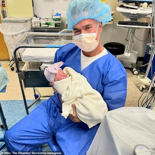 Even with a mask on, Mike looked overjoyed in another photo of himself decked out in scrubs as he cradled little Luna in what appeared to be the delivery room.