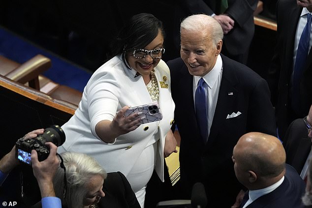 President Joe Biden poses for a photo as he makes his way across the House floor