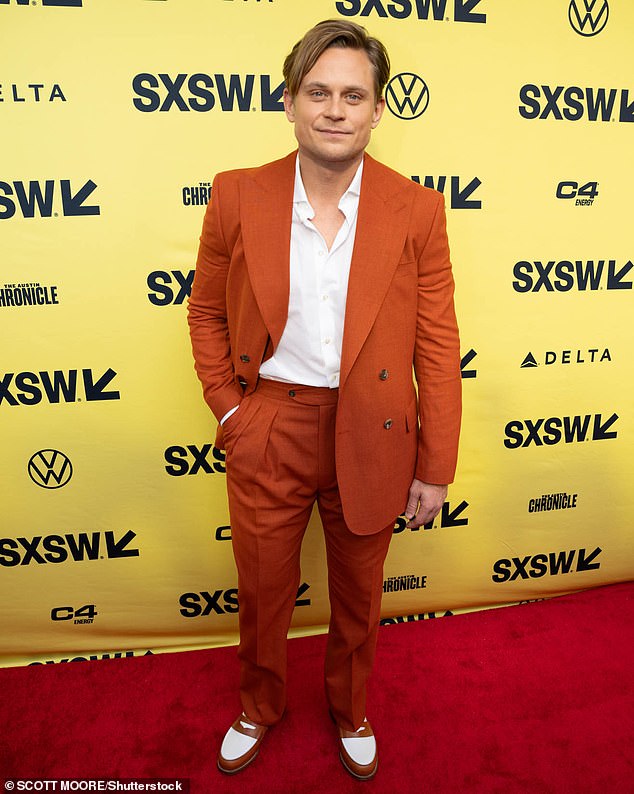 Billy Magnussen stood out in a dark orange double-breasted jacket and two-tone shoes that perfectly matched the shades of his clothes