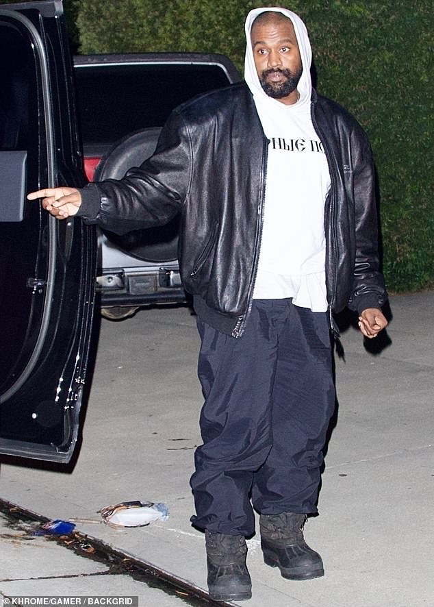 Kanye, meanwhile, was decked out in a white hoodie with the phrase: 'BLACK DOGS' scrawled across the front in Russian.