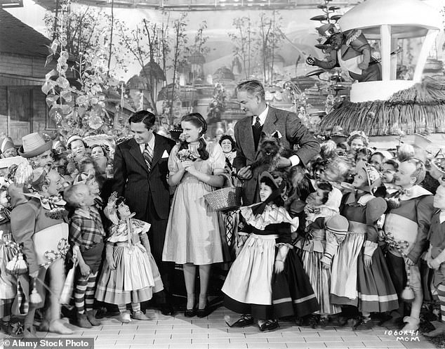 Pictured: Judy Garland on the film set of The Wizard of Oz with producer Mervyn LeRoy and director Victor Fleming, along with ToTo and the munchkins