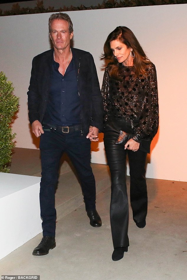 Nineties supermodel Cindy Crawford wore a sparkling black sweater to the star-studded pre-Oscars party as she held hands with her husband of 25 years, Casamigos co-founder Rande Gerber