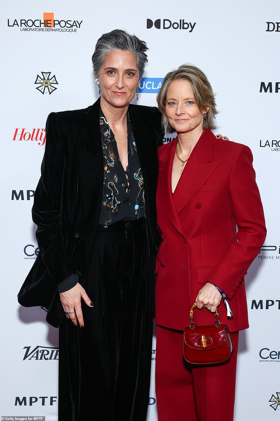 Jodie Foster wore a red suit while holding a small red handbag as she posed with partner Alexandra Hedison, who opted for a black outfit with black nails