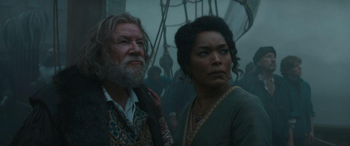 A grizzled older man (Ray Winestone) stands next to a beautiful woman (Angela Bassett) on the deck of a ship.  They both look into the distance, shrouded in mist. 