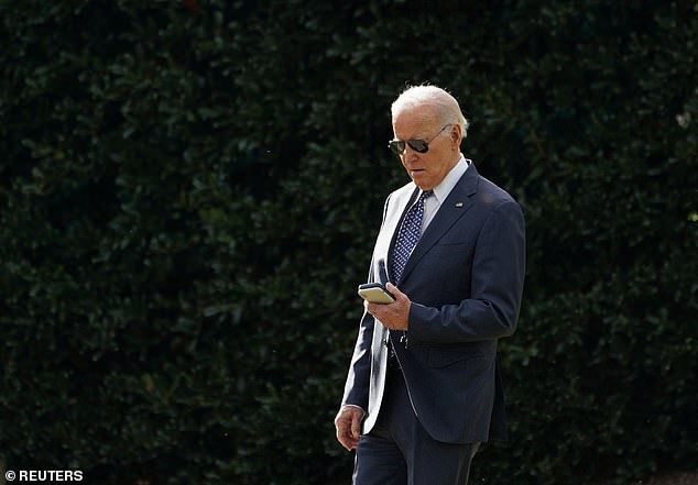 President Joe Biden looks at his phone as he walks from the West Wing to Marine One