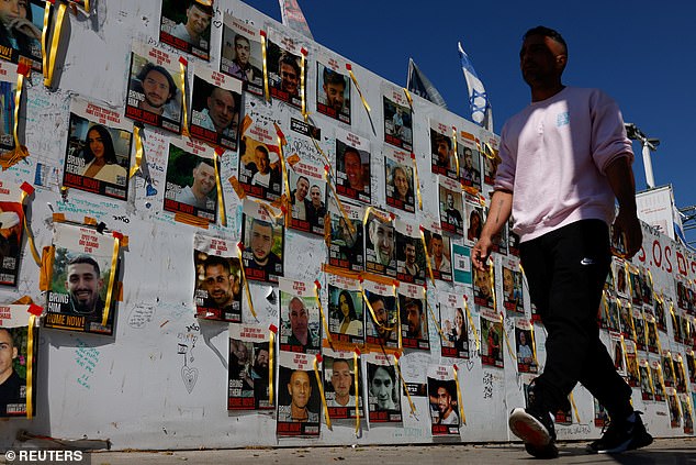 A man walks past signs with photos of hostages kidnapped during the deadly October 7 attack on Israel by Gaza-based Palestinian Islamist group Hamas, in Tel Aviv, Israel