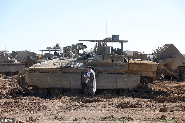 Israeli soldiers pray in front of an armored fighting vehicle in an area near the border with the Gaza Strip, in an undisclosed location in southern Israel