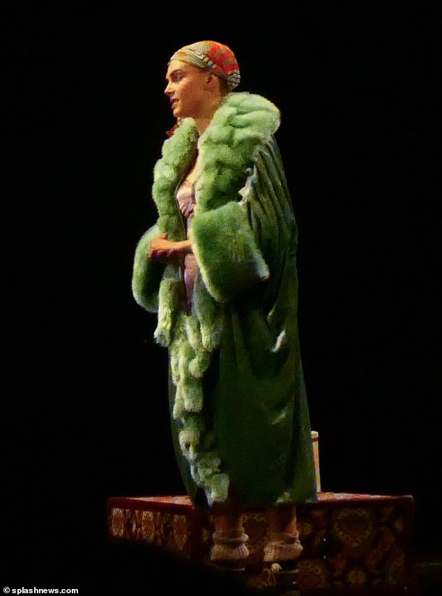 In another scene, Cara was dressed in an elaborate green fur coat and a patterned headscarf