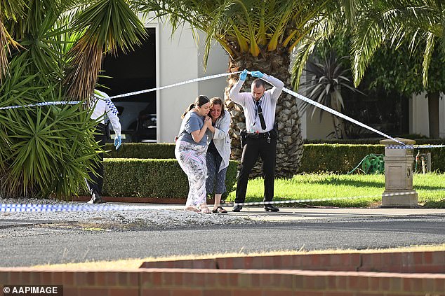 The woman (centre) was treated by paramedics as she was removed from the scene