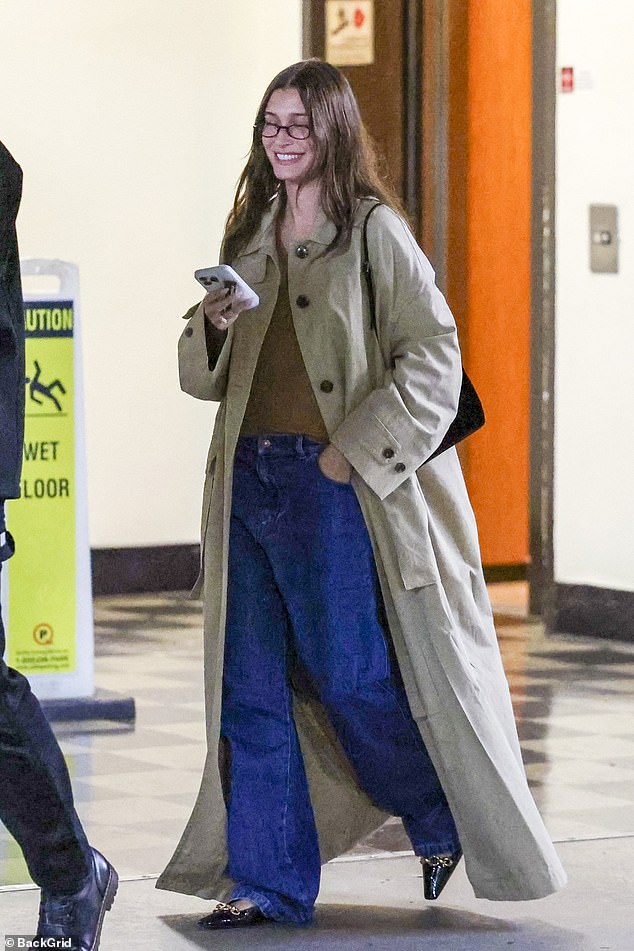 The 27-year-old model wore a long beige trench coat over a brown top and flared jeans, but kept her ring finger hidden in the pocket of her pants