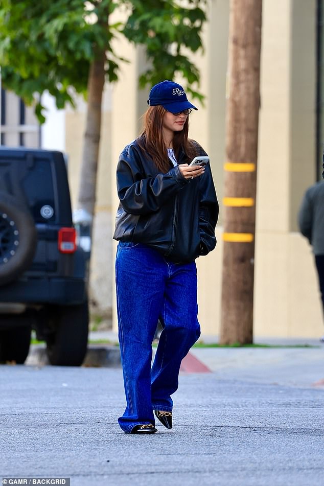 Once again she was casual cool in an oversized black leather jacket, a navy blue baseball cap, sunglasses and the same jeans and shoes