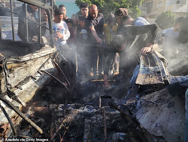 Palestinians inspect the damage of a destroyed pick-up truck loaded with dates as a result of the Israeli attack in Rafah