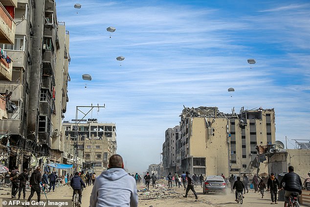 Palestinians run through a street as humanitarian aid is dropped in Gaza City on March 1, 2024