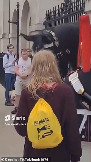 The woman, holding a blue can of Pringles, stood very close to one of the mounted guards