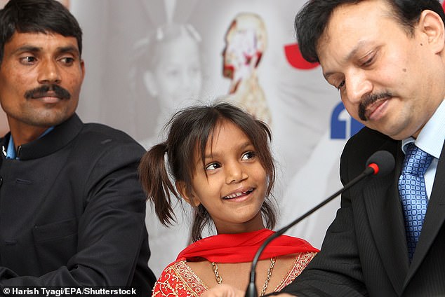 Pinki Sonkar flashes her famous smile at Dr Subodh Kumar Singh (right), who operated on her cleft palate, as her father Rajendera Sonker looks on (left)