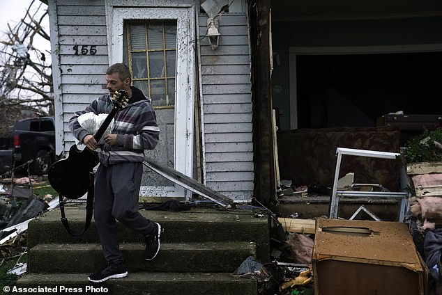 Blaine Schmidt holds his guitar at his damaged home after a heavy storm on Friday, March 15, 2024 in Lakeview, Ohio.  (AP Photo/Joshua A. Bickel)