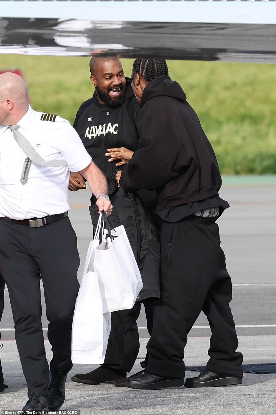 Kanye burst out laughing with a friend on the tarmac and seemed to be in a jovial mood