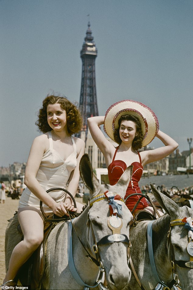 Holidaymakers ride donkeys on Blackpool beach in July 1954