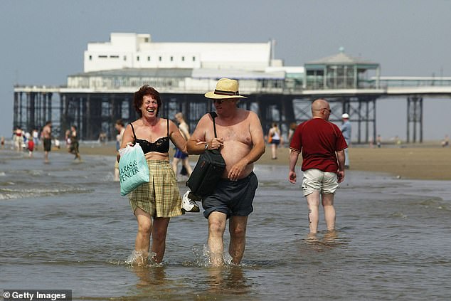 A couple walks in the sea on Blackpool beach on August 6, 2003, when the temperature reached 35.9 degrees Celsius