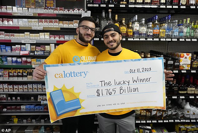 Jonathan Khalil, left, and Chris Khalil, sons of the store's co-owners, hold up a ceremonial check after the winning $1.765 billion Powerball ticket was sold