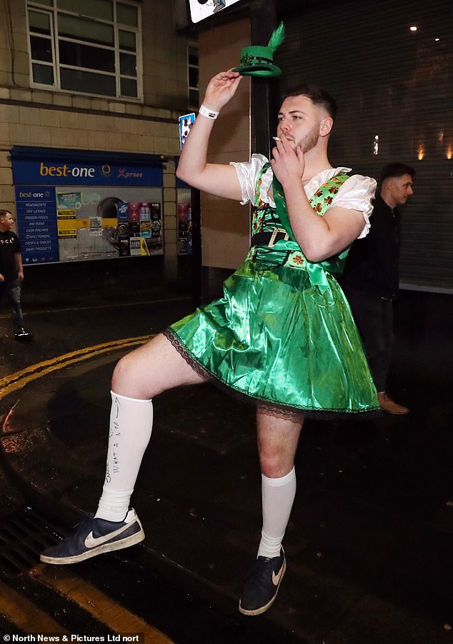 Pictured: a male partygoer wearing a green dress and a small hat, with the message 'what a nob' written on his socks