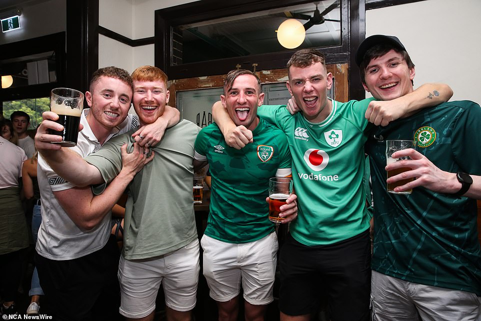 A group of young men proudly raise their glasses to Ireland