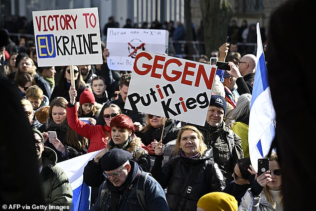 People attend a rally in Berlin near the Russian embassy where voters lined up to cast their votes for the Russian presidential election