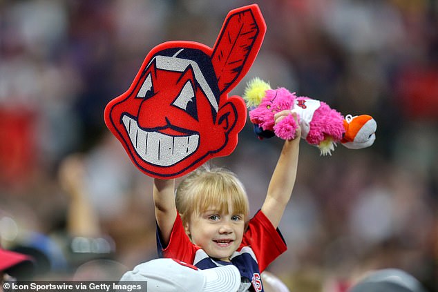 A young Indians fan in the stands holds up a foam Chief Wahoo and Slider doll in 2018