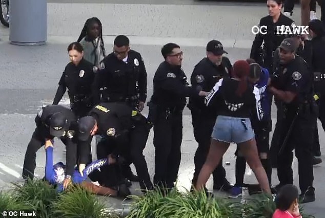 The two women are arrested by the police, with one of them pinned to the ground