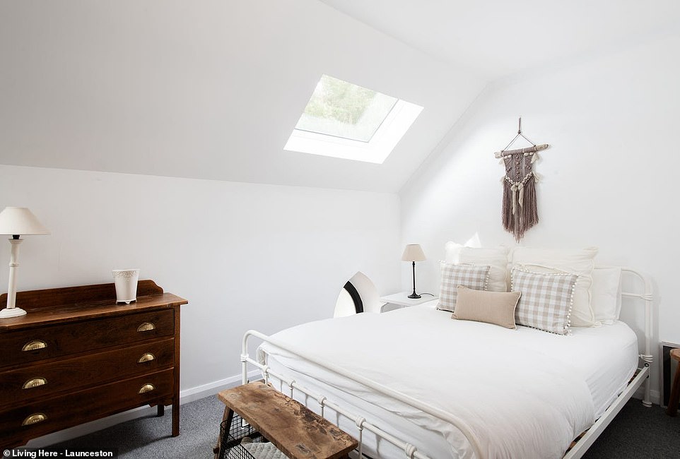 A staircase leads to a mezzanine hallway that overlooks the living space below and provides access to the house's bright bedrooms.