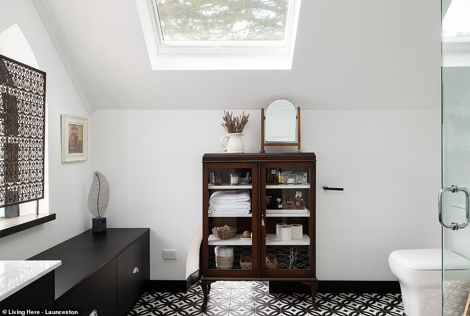 The monochrome theme of the unique home continues in the bathroom with fun patterned tiles, crisp white walls, marble worktops and black wooden joinery