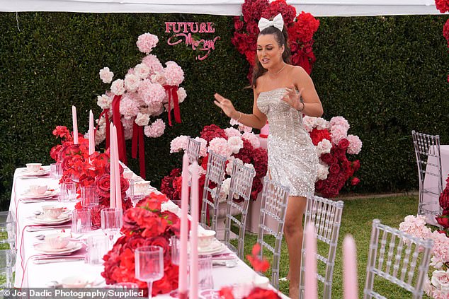 Long tables were set on a lawn and decorated with pink tapered candles and pink and red flowers