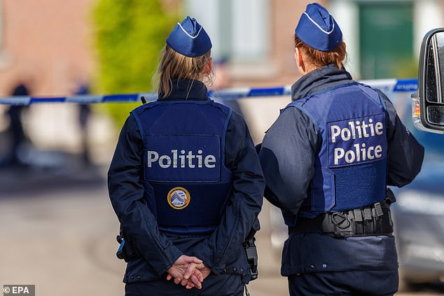 Police officers stand guard at a house where a police officer was killed during an operation in Lodelinsart, Belgium