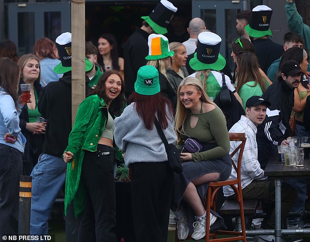 LEEDS: Revelers in leprechaun hats gather outside a pub
