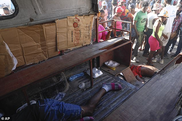 A body lies on the left side of a taxi and another on the ground behind it, after an overnight shooting in the Petion Ville neighborhood of Port-au-Prince, Haiti, Monday, March 18, 2024