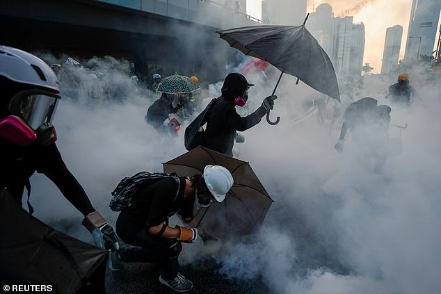 Anti-government protesters protect themselves with umbrellas amid tear gas during a demonstration near the Central Government Complex in Hong Kong, China, September 15, 2019