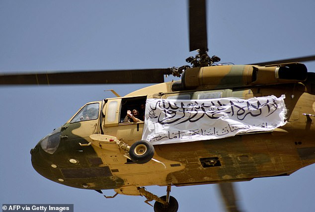 A helicopter with a Taliban flag flies above Taliban supporters who have gathered to celebrate the US withdrawal of all its troops from Afghanistan