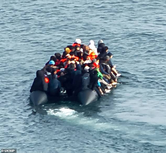 People aboard the inflatable craft are seen clinging on, with many dangling their legs over the side