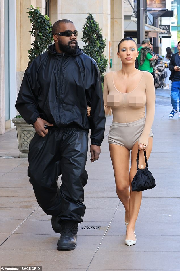 Kanye showed off his titanium teeth as he smiled at his wife, wearing a black baggy jacket, sunglasses and leather-look sweatpants