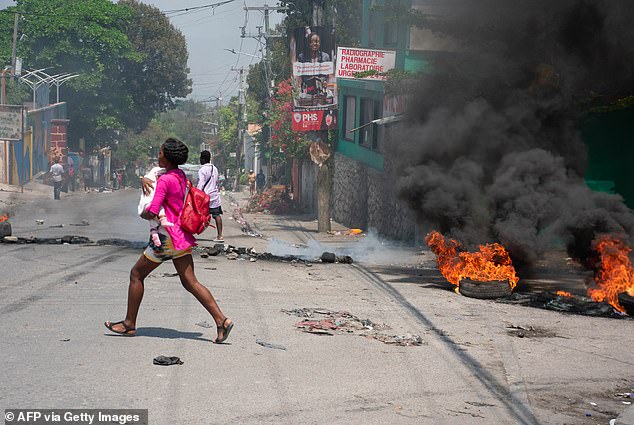 A woman with a child flees the area after gunshots were heard in Port-au-Prince